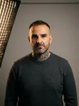 Homme en pull gris foncé sur fond de studio gris